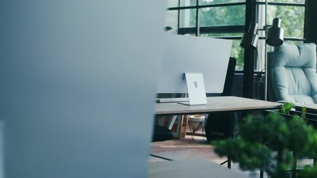 Empty desks with computers at the office with big windows in the background