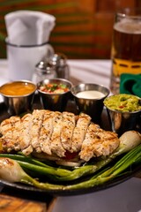 Plate of roasted chicken and steamed green onions, with three small dishes of dipping sauce