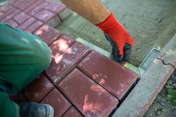 During the laying of paving blocks, the worker checks with a protractor, the correctness of the workmanship.