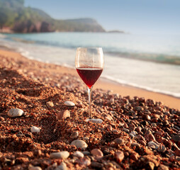 One glass of red wine stands on the beach in Budva Sveti Stefan