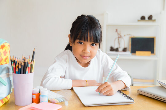 A Girl Coming Home From School Is Sitting And Doing Her Homework In The Living Room.