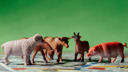 Animales miniatura sobre dólares americanos en fondo verde, concepto de negocio de ganadería y...