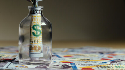 billete de 100 dolares dentro de un frasco de vidrio, sobre mas dolares en la meza, concpeto de...