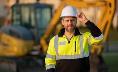 Builder near excavator. Builder worker with excavator. Builder in helmet. Worker in hardhat....