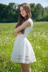 Fototapeta na wymiar Beautiful girl in a flowery meadow in a white dress in summer
