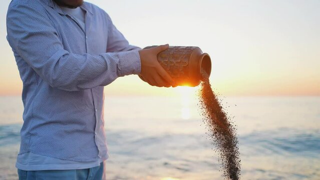 Ceremony a man throws ashes with his hand against the background of the sea close up
