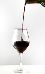 Bottle of red wine being poured into a glass, ready for consumption
