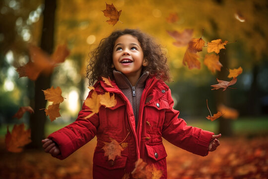 mixed race girl child playing in autumn fall leaves wearing red jacket autumn colours