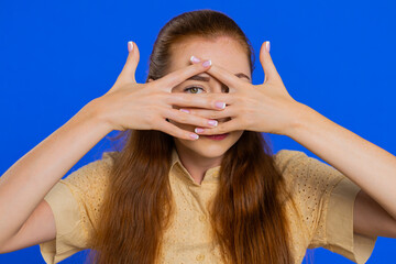 Nosy curious adult woman closing eyes with hand and spying through fingers, hiding and peeping,...