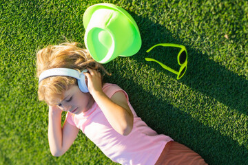 Emotional funny child in t-shirt in headphones in summer park. Children music concept. Little child...