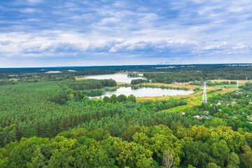 Równina pokryta zielonym lasem. wśród gęstwiny drzew widać dwa jeziora. Niebo jest lekko zachmurzone. Zdjęcie z drona.