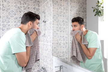 Handsome man washing his face in the bathroom. Morning routine and hygiene concept	