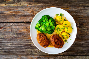 Seared pork meatballs with boiled potatoes and  broccoli  on wooden table