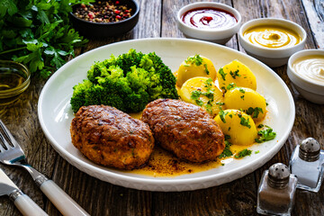 Seared pork meatballs with boiled potatoes and  broccoli  on wooden table