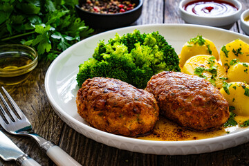 Seared pork meatballs with boiled potatoes and  broccoli  on wooden table
