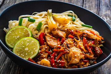 Asian food - chicken nuggets, noodles and stir fried vegetables on wooden table
