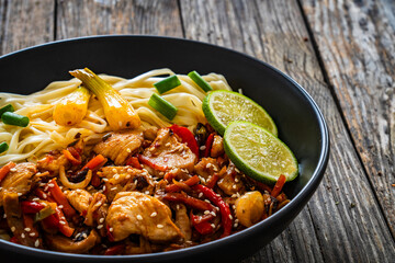 Asian food - chicken nuggets, noodles and stir fried vegetables on wooden table
