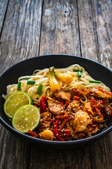 Asian food - chicken nuggets, noodles and stir fried vegetables on wooden table
