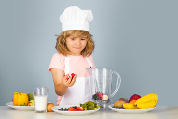 Kid boy in chef hat and apron cooking preparing meal. Little cook with vegetables at kitchen. Natural kids food.