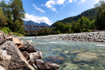 Flowing Skykomish river with cascade mountains and old bridge in background
