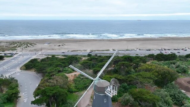 Dolly shot aerial over Murphy Windmill with Pacific Ocean and crashing waves