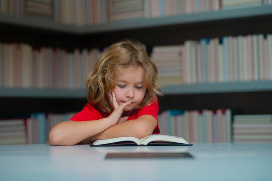 Thinking school kid. Schoolboy reading book in library. Kids development, learn to read. Pupil reading books in a school library. School child doing homework, study hard.