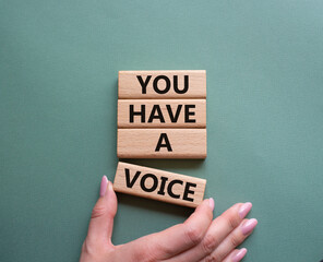You have a voice symbol. Concept words You have a voice on wooden blocks. Beautiful grey green background. Businessman hand. Business and You have a voice concept. Copy space.