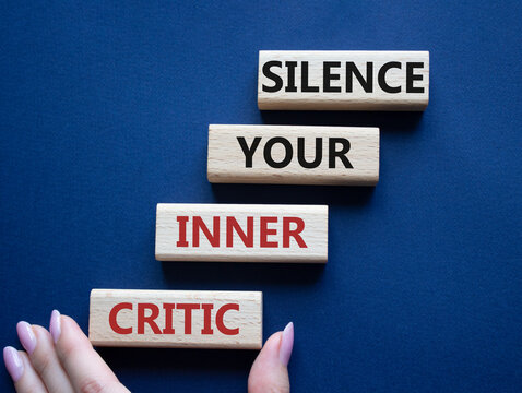 Silence your inner critic symbol. Wooden blocks with words Silence your inner critic. Beautiful deep blue background. Businessman hand. Business and Silence your inner critic concept. Copy space.