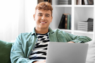 Young redhead man using laptop on sofa at home, closeup