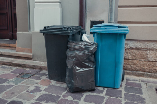 Rows of garbage cans of different colors in an alley in the city center, near a city cafe or restaurant. High quality photo