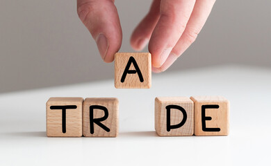 Hand flips cubes and changes the word 'train' to 'trade'. Beautiful wooden table, white background, copy space. Business concept.