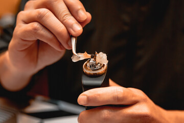 Cleaning the cotton of a vape with a tweezers in the vape store.