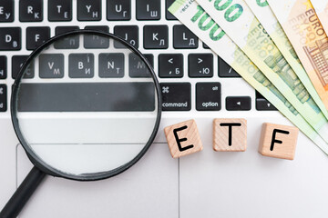 ETF - text on wooden cubes on a cold grey light background with stacks coins