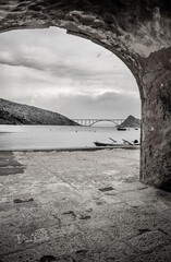 View on a bridge to an island through an arch of a historic ruins building on the Krk island in Croatia