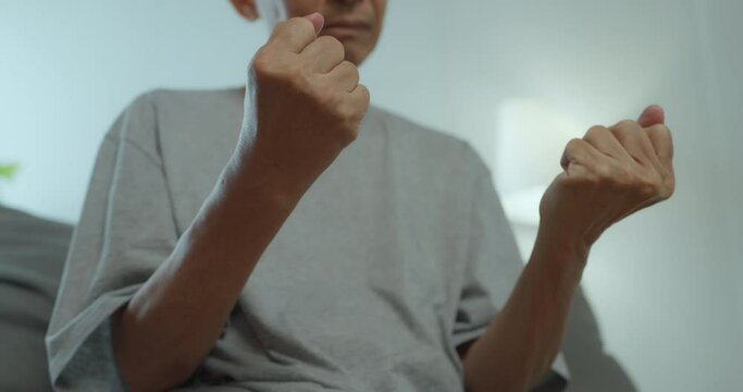 Asian senior man has tingling and numbness in his hand which causes beriberi. Mature asian man with wrist pain at home.