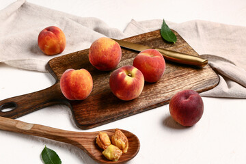 Wooden board with sweet peaches on white background