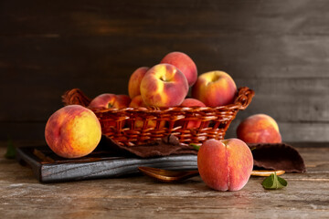 Wicker basket with sweet peaches on wooden background