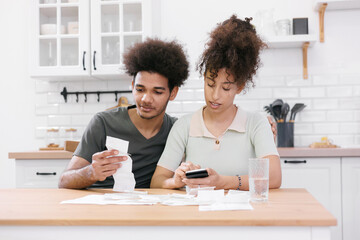 man and woman couple pay electricity and rent bills. African American young married person in...