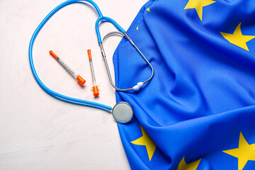 Flag of European Union with stethoscope and insulin syringes on color background