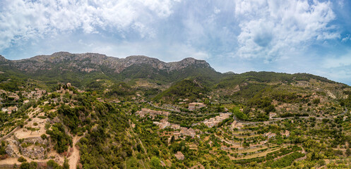 The panoramic view of Deia at the Island Mallorca shows the treelined mountain high point near the ocean, Mountain and Bay on the mediterranean coastline,  skyline Serra de Tramuntana