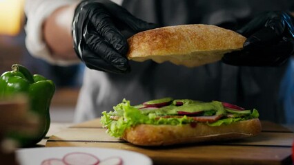 Breakfast, cooking master attentively Cooking a sandwich at the culinary workplace. Efficient hamburger man Sliced prepares vegetables for a sandwich showing his skill in making food, tomato - Powered by Adobe