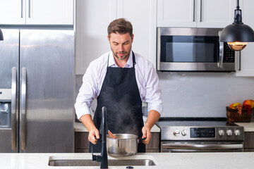 Cooking food at home. Man in kitchen preparing a meal. Male cook preparing food in kitchen at home. Chef cooking meal. Man cooking food, kitchen pot food plate. Man preparing soup on kitchen interior.