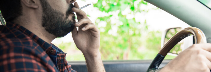 man is smoking cigarette and driving  car