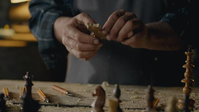 Workplace, master concentrated Holds a chess piece in his hands looks at the result In a carpentry workshop Slow motion A talented craftsman Works with wood blanks In a production room, slow motion