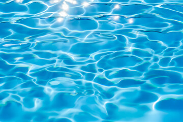 Fototapeta na wymiar Vibrant blue water surface with captivating sunlit reflections, closeup view of a swimming pool