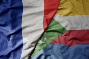 big waving realistic national colorful flag of france and national flag of comoros .