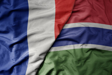 big waving realistic national colorful flag of france and national flag of gambia .