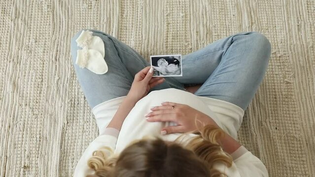 Pregnant blond girl holds ultrasound of baby embryo