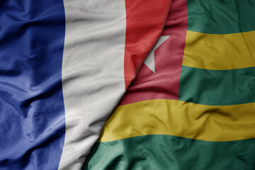 big waving realistic national colorful flag of france and national flag of togo .