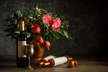 Bouquet of flowers and fruits of pomegranate, wine, torah scroll, concept of jewish new year - rosh...